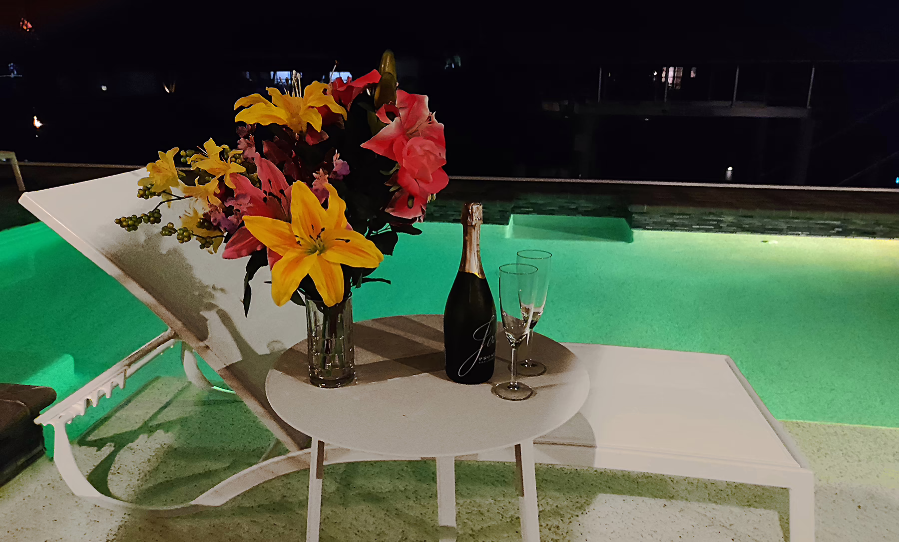 Beleuchteter Pool der Villa Dandelion in Cape Coral mit Blumenarrangement.